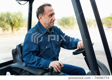 Elderly man of winery goes on loader 74096754