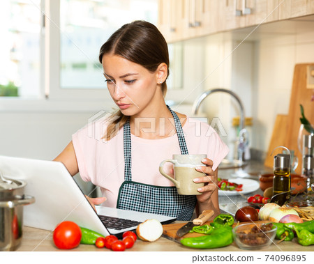 Housewife drinking coffee and using laptop Housewife drinking coffee and using laptop 74096895