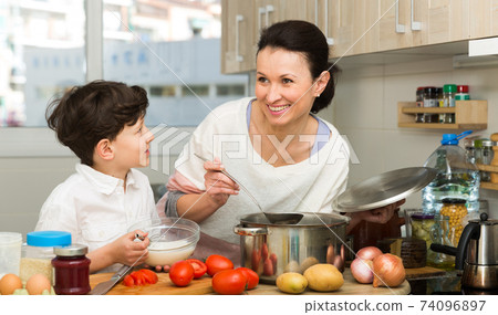 Woman and her son preparing food 74096897