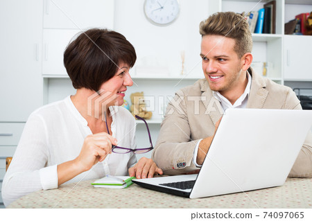Positive mom and son consider software on laptop Positive mom and son consider software on laptop 74097065