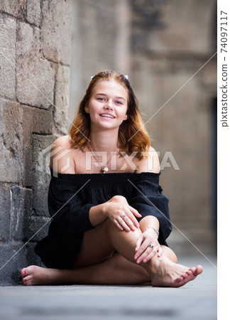 young female sitting barefoot near the stone wall young female sitting barefoot near the stone wall 74097117