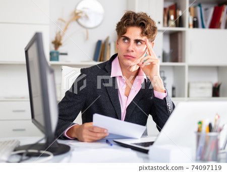 intelligent man working on his laptop in white room 74097119