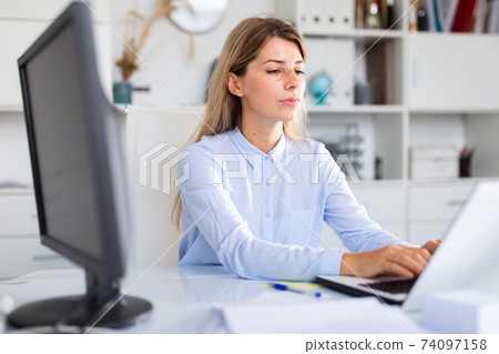 woman working on her laptop in white room 74097158