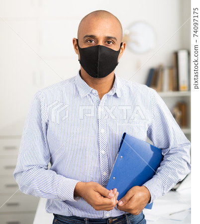 Businessman in protective mask makes notes in document 74097175