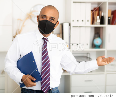 Portrait of positive business man in protective mask with folder of documents 74097212