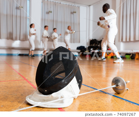 Closeup of fencing mask and rapier on floor in gym 74097267