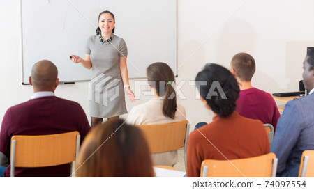 Positive woman business trainer at seminar in university audience Positive woman business trainer at seminar in university audience 74097554