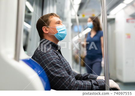 Man in medical mask riding in subway car Man in medical mask riding in subway car 74097555