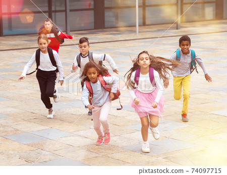 Team of positive schoolchildren running in race in the street 74097715