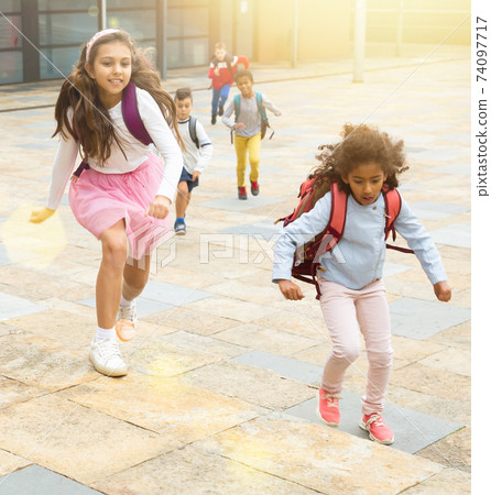 Team of positive schoolchildren running in race in the street 74097717