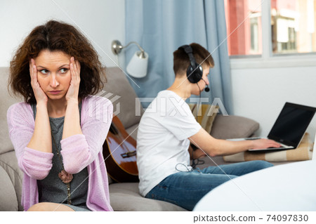 Worried mother with son carried away with laptop Worried mother with son carried away with laptop 74097830