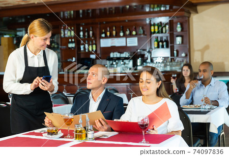 Polite waitress taking order from couple in pizza restaurant Polite waitress taking order from couple in pizza restaurant 74097836