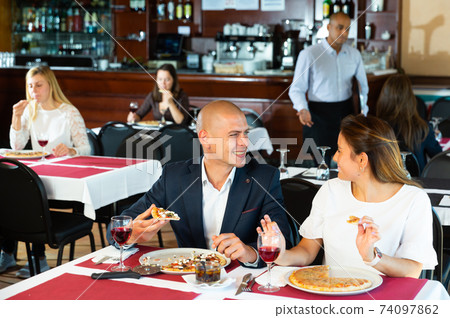 Couple enjoying delicious pizza and wine at restaurant Couple enjoying delicious pizza and wine at restaurant 74097862