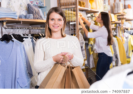 Young woman carrying paper bags with purchases in fashion store Young woman carrying paper bags with purchases in fashion store 74097887