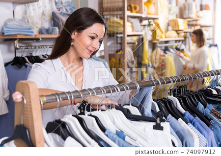 Woman customer choosing blue blouse in the fashion store Woman customer choosing blue blouse in the fashion store 74097912