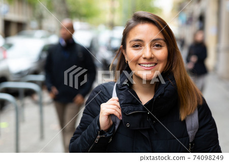 Smiling woman walking outdoors at cold day 74098249