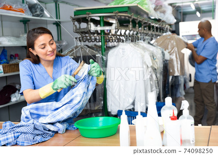 Focused woman drycleaner removing spots and stains Focused woman drycleaner removing spots and stains 74098250