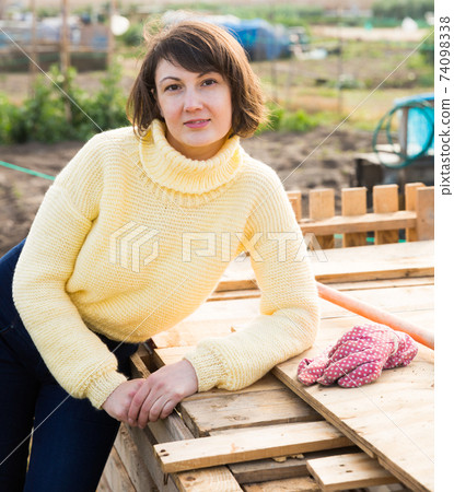 Girl in a yellow sweater works in the garden of a country house 74098338
