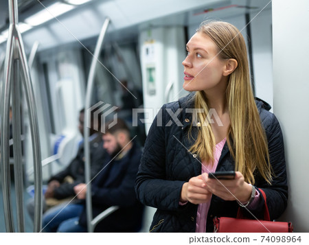 Young woman with phone in subway car 74098964