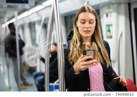 Young woman with phone in subway car Young woman with phone in subway car 74099010