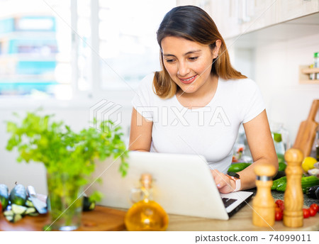 Nice latino woman planning to cook, looking for recipe on internet Nice latino woman planning to cook, looking for recipe on internet 74099011