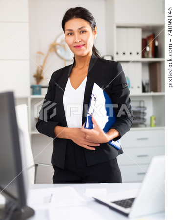 Office worker is standing with documents before signing it in office Office worker is standing with documents before signing it in office 74099146