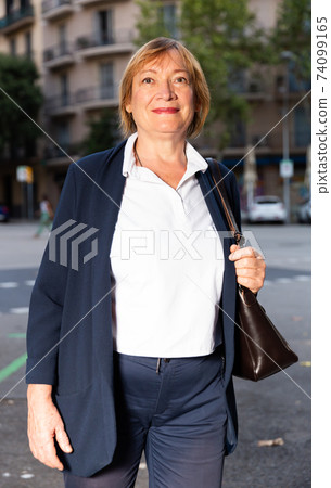 Senior woman walking on street Senior woman walking on street 74099165