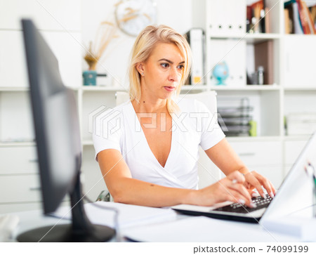 Successful business woman using laptop at workplace Successful business woman using laptop at workplace 74099199