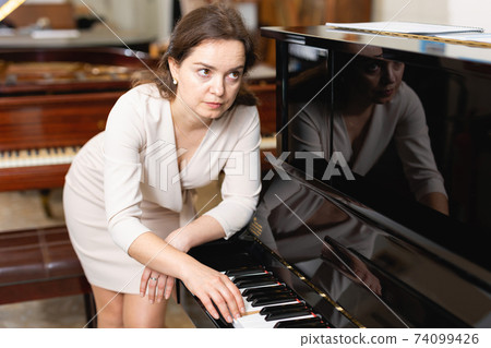 Young woman buys a piano in a music store Young woman buys a piano in a music store 74099426