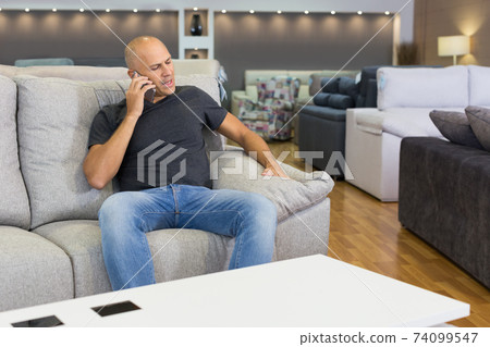Man sitting and testing new sofa Man sitting and testing new sofa 74099547