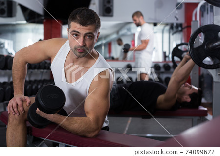 Man doing exercises with dumbbells at gym Man doing exercises with dumbbells at gym 74099672