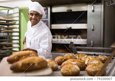 Man holding bread on peel in bakery 74100007