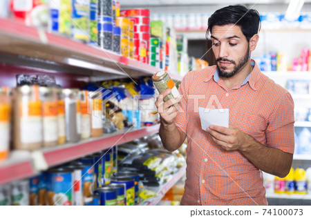 Man is choosing Oregano using note list in supermarket. Man is choosing Oregano using note list in supermarket. 74100073
