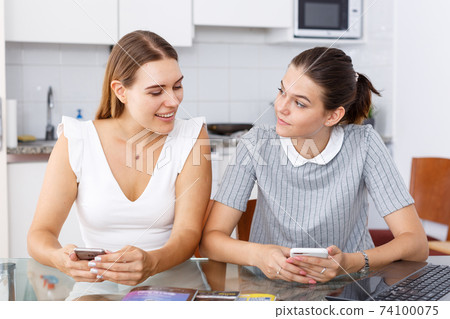 Girls talking and looking at smartphone Girls talking and looking at smartphone 74100075