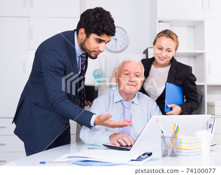 Employees are demonstrating reports on laptop to mature boss Employees are demonstrating reports on laptop to mature boss 74100077