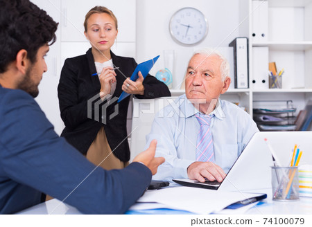 Old man is talking to colleague Old man is talking to colleague 74100079