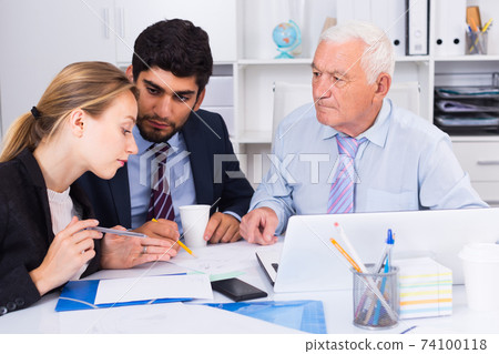 Employees are writing financial reports and discussing with mature boss Employees are writing financial reports and discussing with mature boss 74100118
