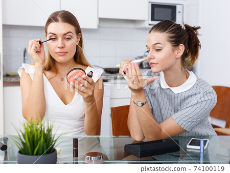 Grls having conversation and applying cosmetics 74100119