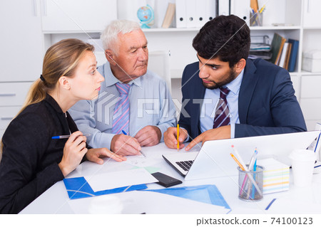 Employees are writing financial reports and discussing with mature boss Employees are writing financial reports and discussing with mature boss 74100123