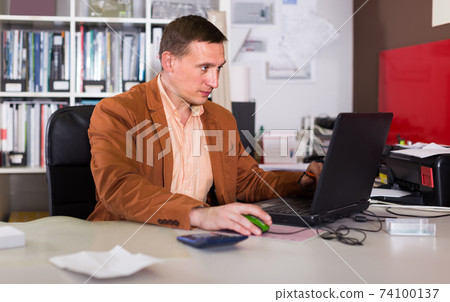Portrait of concentrated manager working in agency office Portrait of concentrated manager working in agency office 74100137