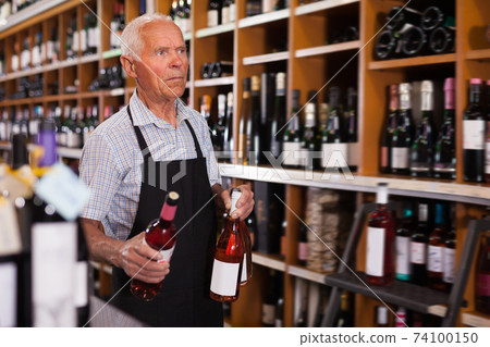 Modern male vintner working in modern wine shop Modern male vintner working in modern wine shop 74100150