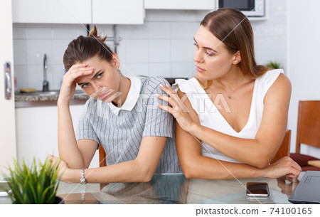 Upset woman holding head after conflict, female friend tries reconcile Upset woman holding head after conflict, female friend tries reconcile 74100165