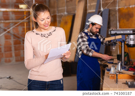 Architect with drawing checks the work of builders 74100187