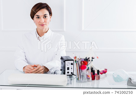 Smiling female manicurist showing her workplace Smiling female manicurist showing her workplace 74100250