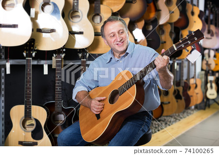 Man playing on acoustic guitar Man playing on acoustic guitar 74100265