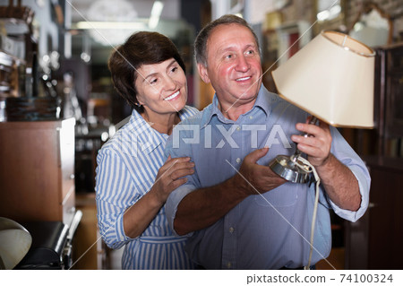 Mature family couple choosing vintage lamp Mature family couple choosing vintage lamp 74100324