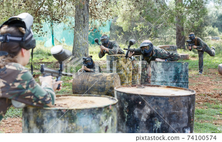 Two opposing teams in camouflage playing paintball against each other 74100574