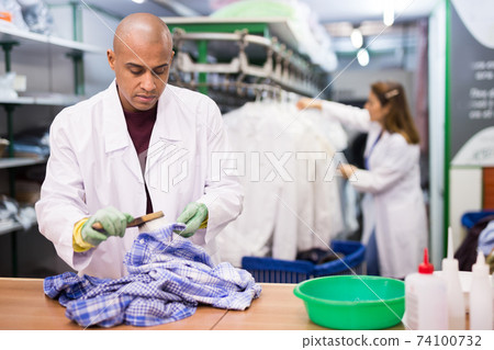 Skilled man working in dry cleaner Skilled man working in dry cleaner 74100732
