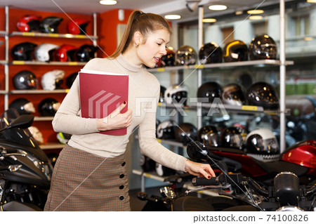 Woman choosing new motorbike Woman choosing new motorbike 74100826
