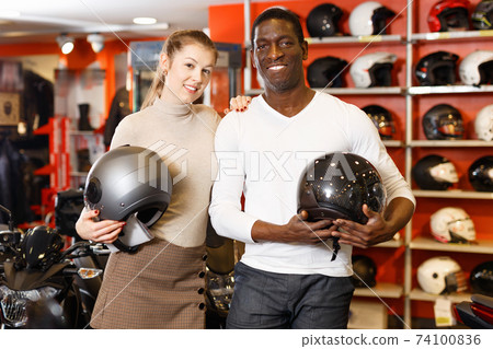 Smiling female and male customers satisfied with purchases in motorcycle shop 74100836